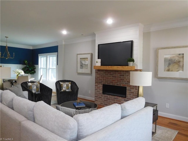 living area with a fireplace, crown molding, wood finished floors, and baseboards