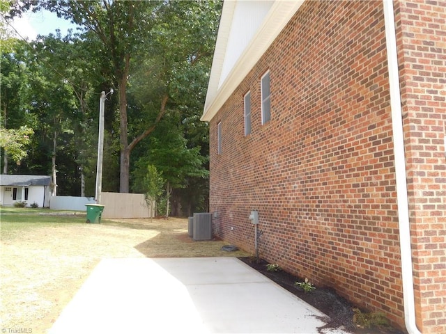 view of home's exterior with a patio area, brick siding, central AC unit, and fence