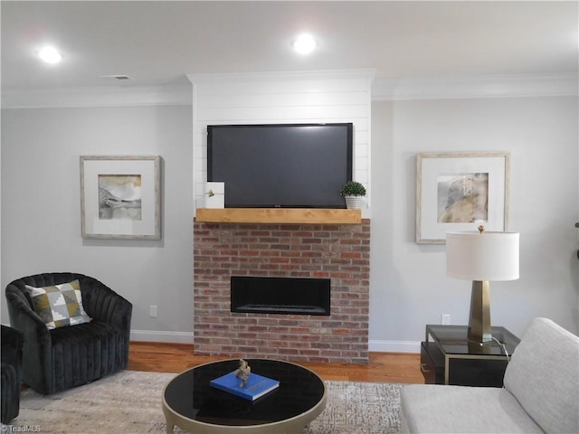 living area with wood finished floors, baseboards, and ornamental molding