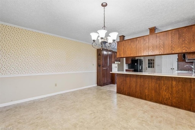 kitchen featuring black fridge, ornamental molding, decorative light fixtures, kitchen peninsula, and a chandelier