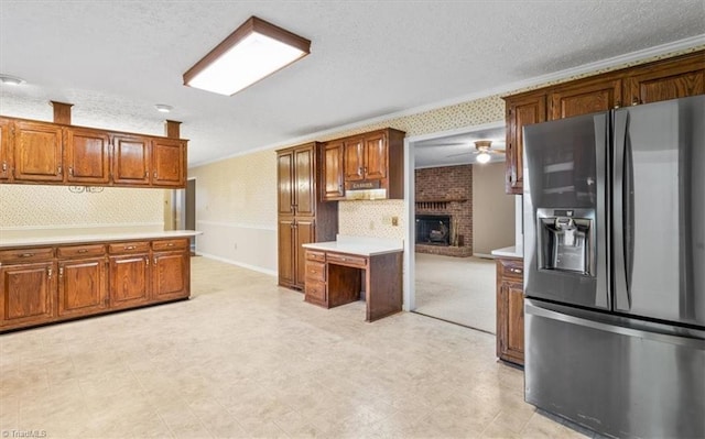 kitchen featuring ceiling fan, stainless steel fridge, a textured ceiling, and a fireplace