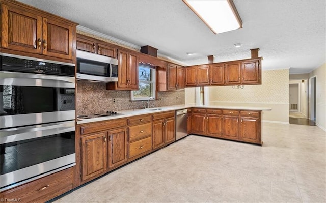 kitchen with sink, decorative backsplash, a textured ceiling, kitchen peninsula, and stainless steel appliances