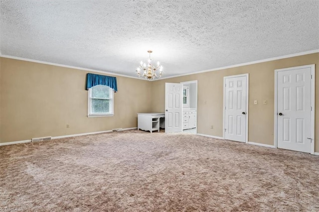 carpeted spare room featuring crown molding, a chandelier, and a textured ceiling