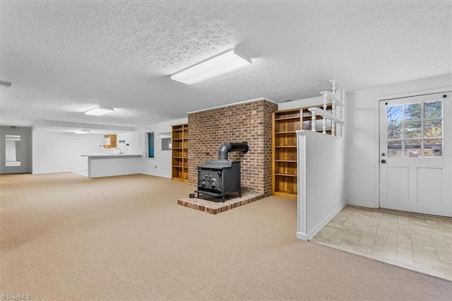 unfurnished living room featuring a wood stove, light carpet, and a textured ceiling