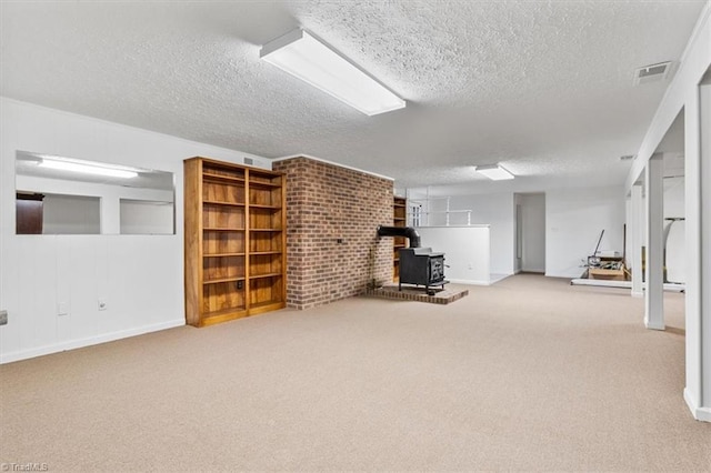 basement with a wood stove, light carpet, and a textured ceiling