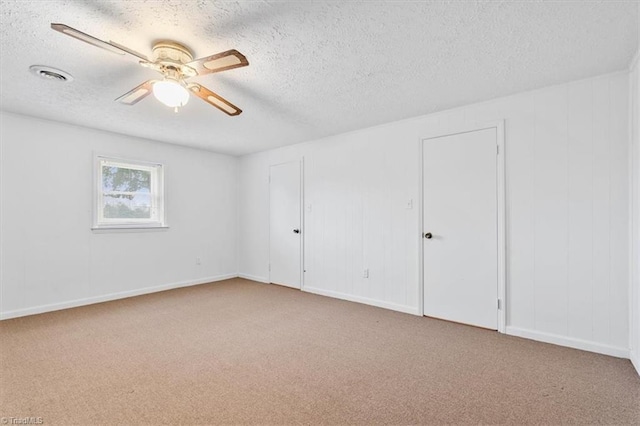 carpeted empty room featuring ceiling fan and a textured ceiling