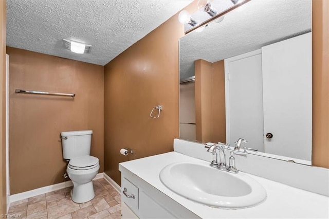 bathroom featuring vanity, a textured ceiling, and toilet