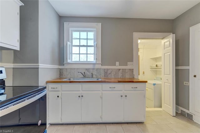 kitchen featuring white cabinetry, sink, electric range oven, independent washer and dryer, and wooden counters