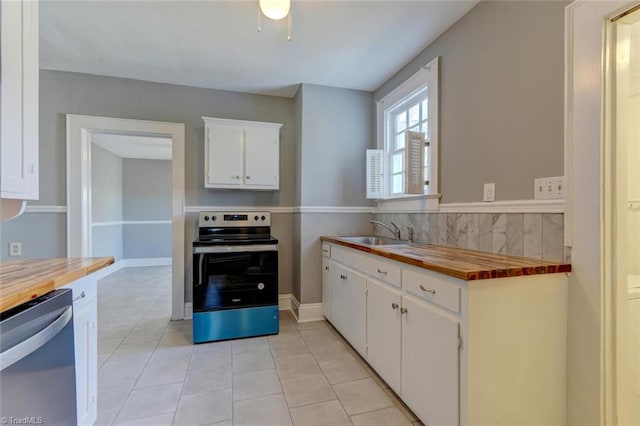 kitchen with appliances with stainless steel finishes, white cabinetry, wooden counters, and sink