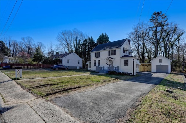 view of front of house featuring a garage, a front lawn, and an outbuilding