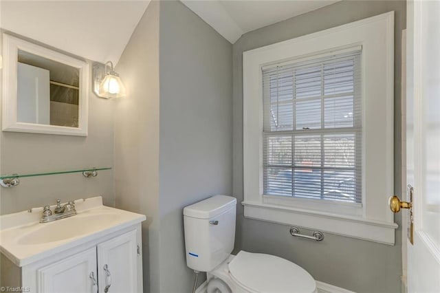 bathroom with vaulted ceiling, toilet, and vanity