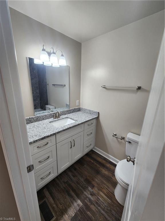 bathroom with hardwood / wood-style floors, vanity, and toilet