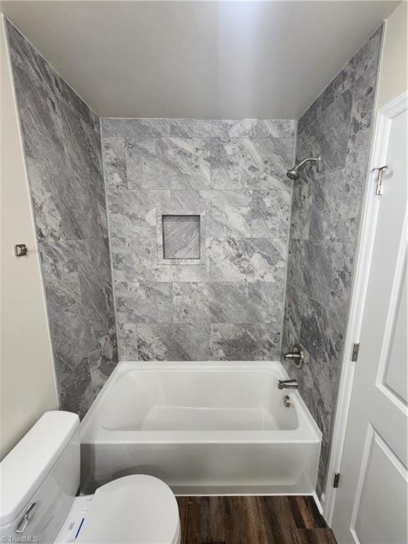 bathroom with toilet, wood-type flooring, and tiled shower / bath