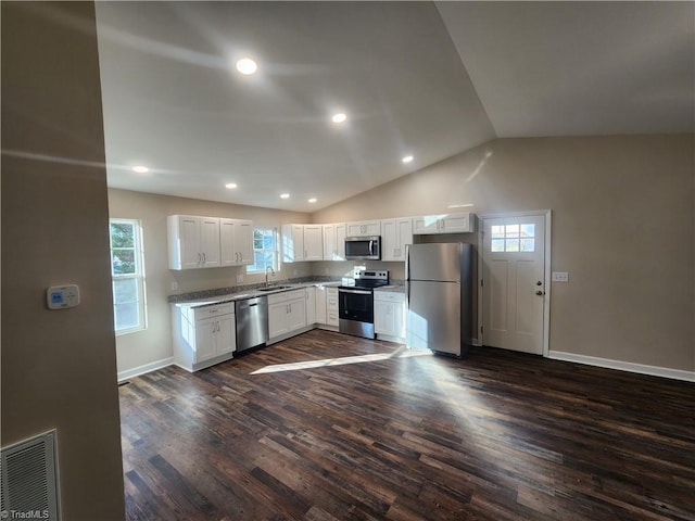 kitchen with vaulted ceiling, stainless steel appliances, white cabinetry, and dark wood-type flooring