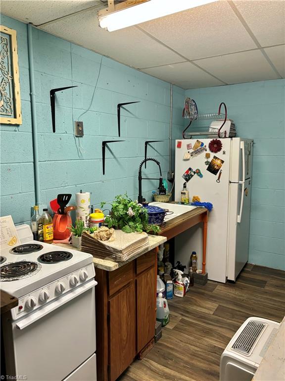 kitchen with dark wood-type flooring, white appliances, and a drop ceiling