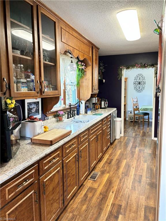 kitchen with light stone counters, dark wood-type flooring, a textured ceiling, and sink