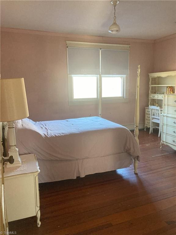 bedroom with crown molding and dark hardwood / wood-style floors