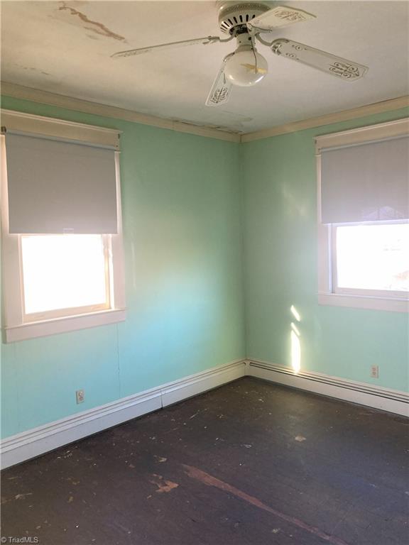 empty room with baseboard heating, ceiling fan, and ornamental molding