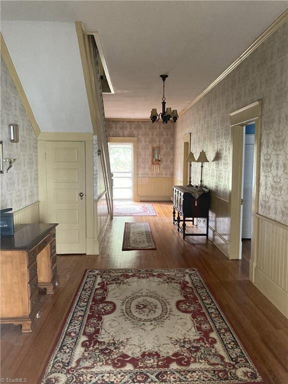 corridor featuring crown molding, dark hardwood / wood-style floors, and a notable chandelier