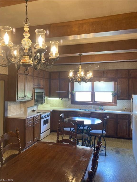 kitchen with pendant lighting, a notable chandelier, white appliances, and decorative backsplash