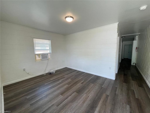 spare room featuring baseboards, cooling unit, and dark wood-type flooring