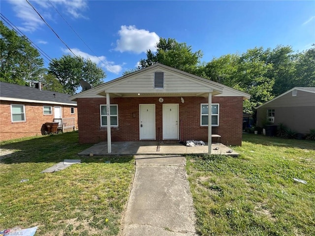 bungalow-style home with covered porch, brick siding, and a front lawn