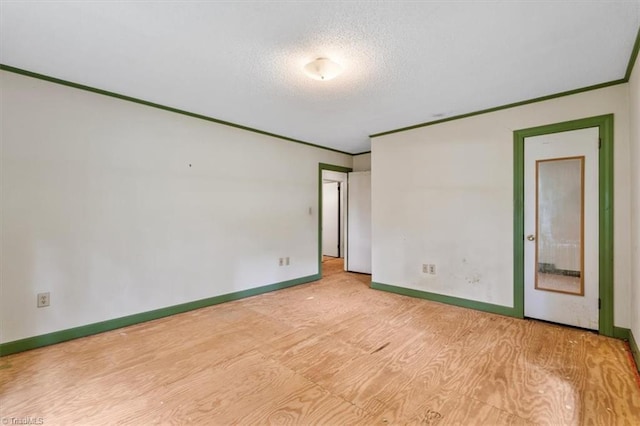 spare room featuring a textured ceiling, baseboards, wood finished floors, and crown molding