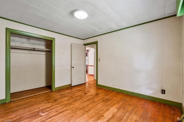 unfurnished bedroom with hardwood / wood-style floors, a closet, and baseboards