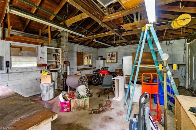 misc room featuring unfinished concrete floors and concrete block wall