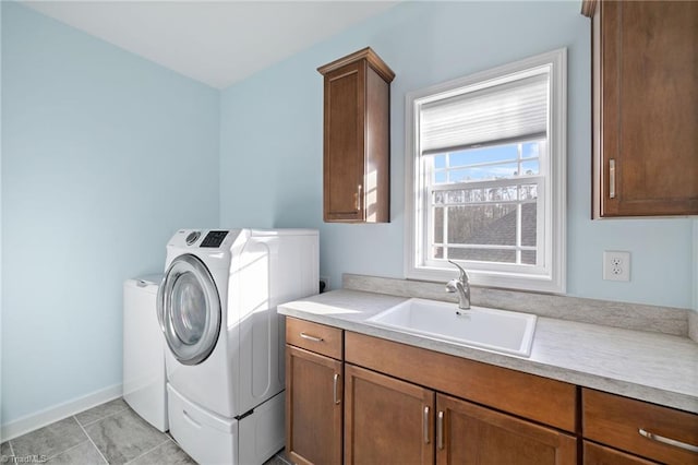 clothes washing area featuring sink, washer and clothes dryer, and cabinets