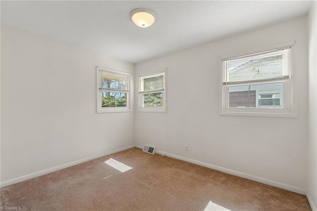 carpeted empty room with baseboards, visible vents, and a textured ceiling