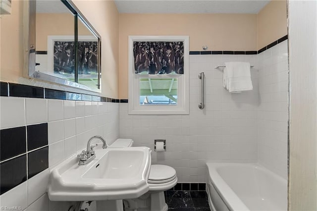 bathroom featuring a sink, toilet, tile walls, and shower / washtub combination