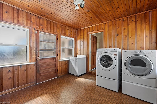 clothes washing area with laundry area, wood ceiling, wood walls, and washer and clothes dryer