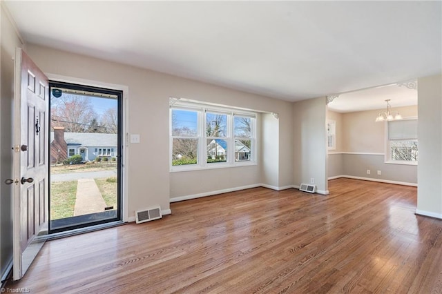 interior space featuring a notable chandelier, visible vents, baseboards, and wood finished floors