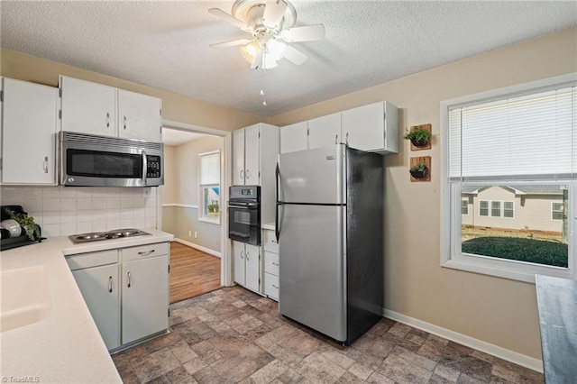 kitchen with tasteful backsplash, baseboards, light countertops, stone finish floor, and black appliances