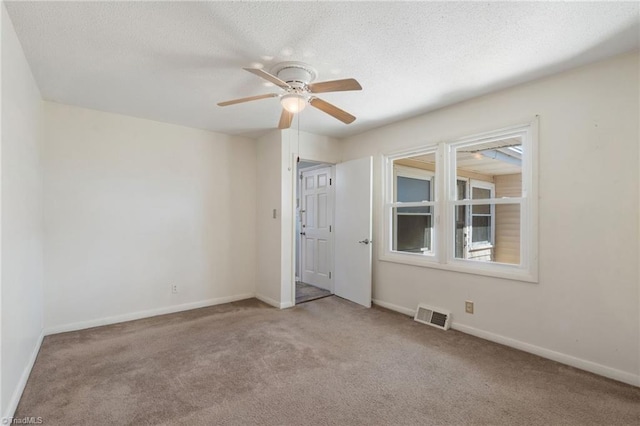 spare room with baseboards, visible vents, carpet floors, and a textured ceiling