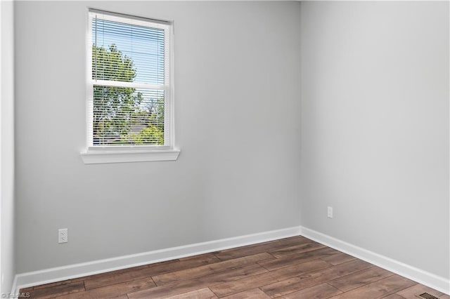 unfurnished room featuring baseboards, dark wood-type flooring, and a wealth of natural light