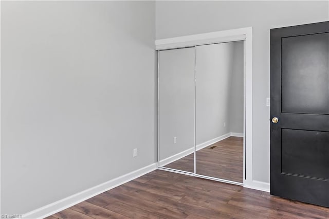 unfurnished bedroom with baseboards, a closet, and wood finished floors