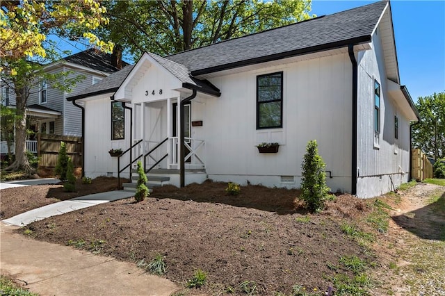 view of front of home with a shingled roof, fence, and crawl space