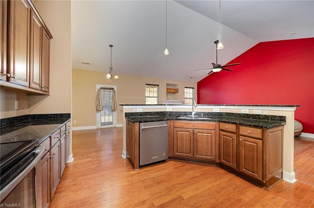 kitchen featuring light hardwood / wood-style floors, appliances with stainless steel finishes, decorative light fixtures, dark stone countertops, and sink