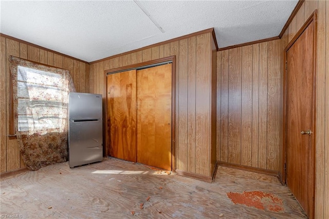 kitchen featuring crown molding, stainless steel fridge, and wood walls