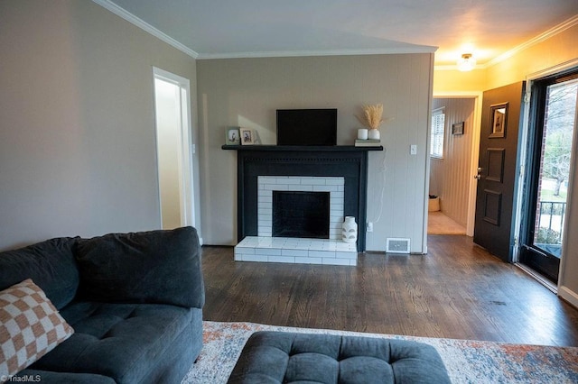 living room with dark hardwood / wood-style floors, crown molding, and a brick fireplace