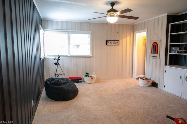 living area with carpet flooring, ceiling fan, and ornamental molding