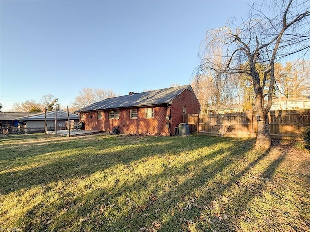 rear view of property featuring a lawn and central air condition unit