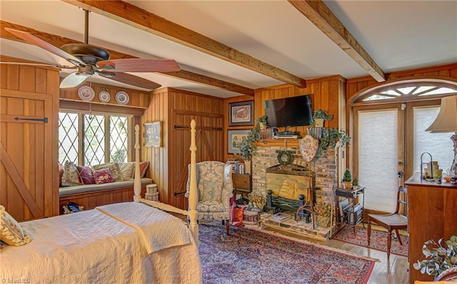 bedroom featuring beamed ceiling, access to outside, light hardwood / wood-style flooring, and wooden walls