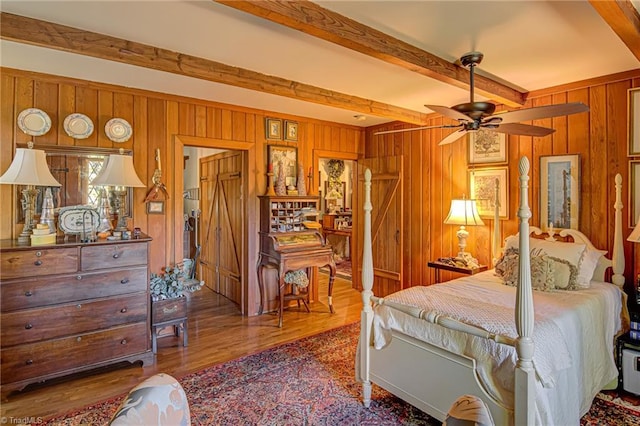 bedroom featuring beam ceiling, wooden walls, and hardwood / wood-style floors