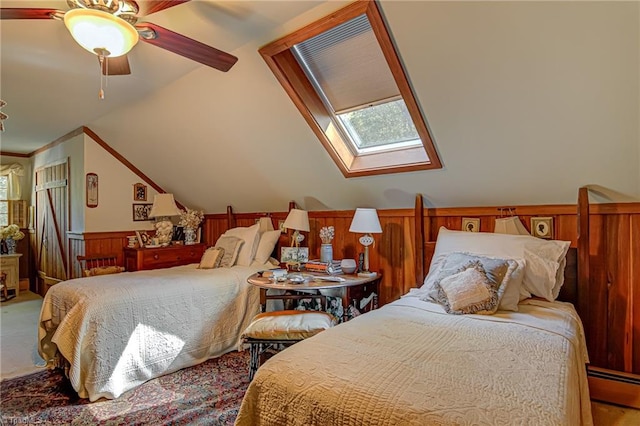 bedroom featuring wood walls, carpet, ceiling fan, baseboard heating, and lofted ceiling with skylight