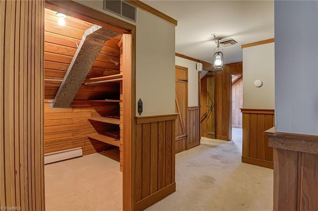 hallway featuring wooden walls, light colored carpet, and a baseboard radiator