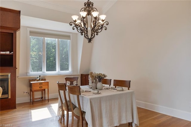 dining area featuring light hardwood / wood-style flooring, ornamental molding, and an inviting chandelier