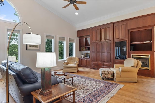 living room featuring ceiling fan, high vaulted ceiling, ornamental molding, and light wood-type flooring